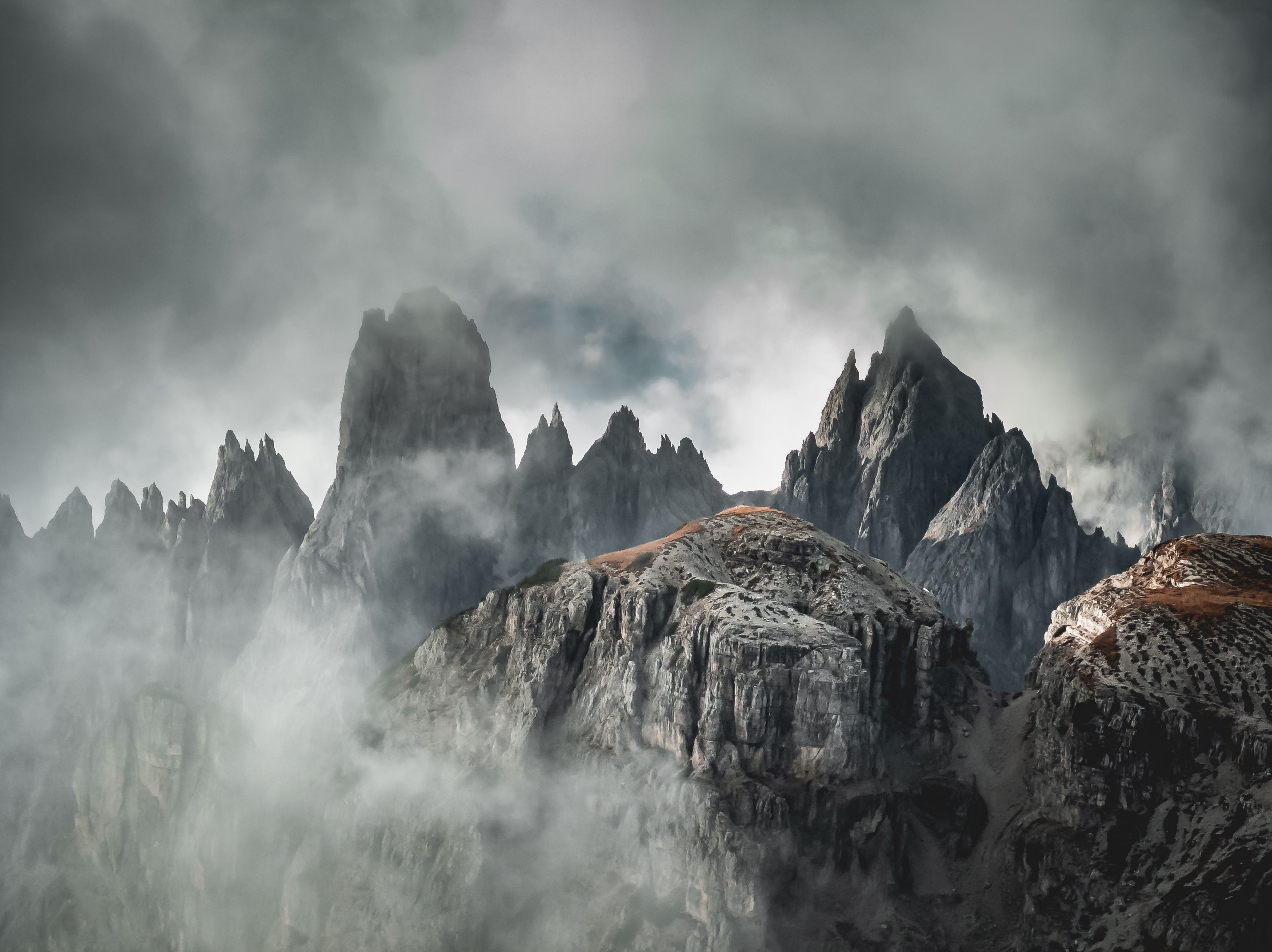 Uma foto nas Dolomitas de uma cadeia de montanhas envolta em névoa, num visual bem misterioso.